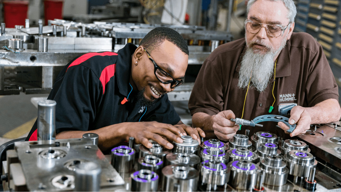 A teacher and adult student working together over machinery.